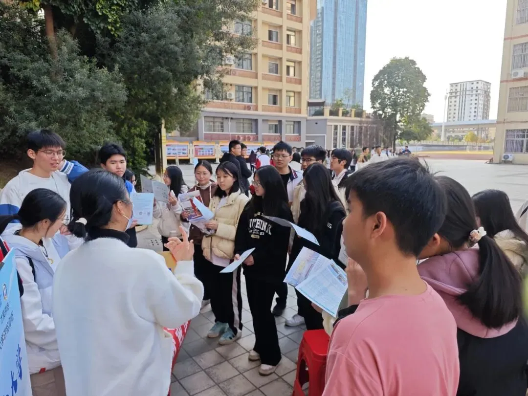 大学生在咨询摊位前与学弟学妹交流
